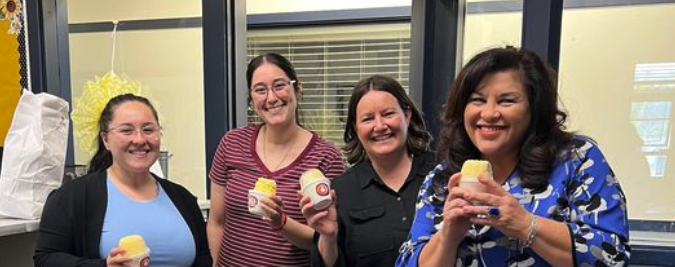 4 teacher smiling with yogurt in the school's front office 