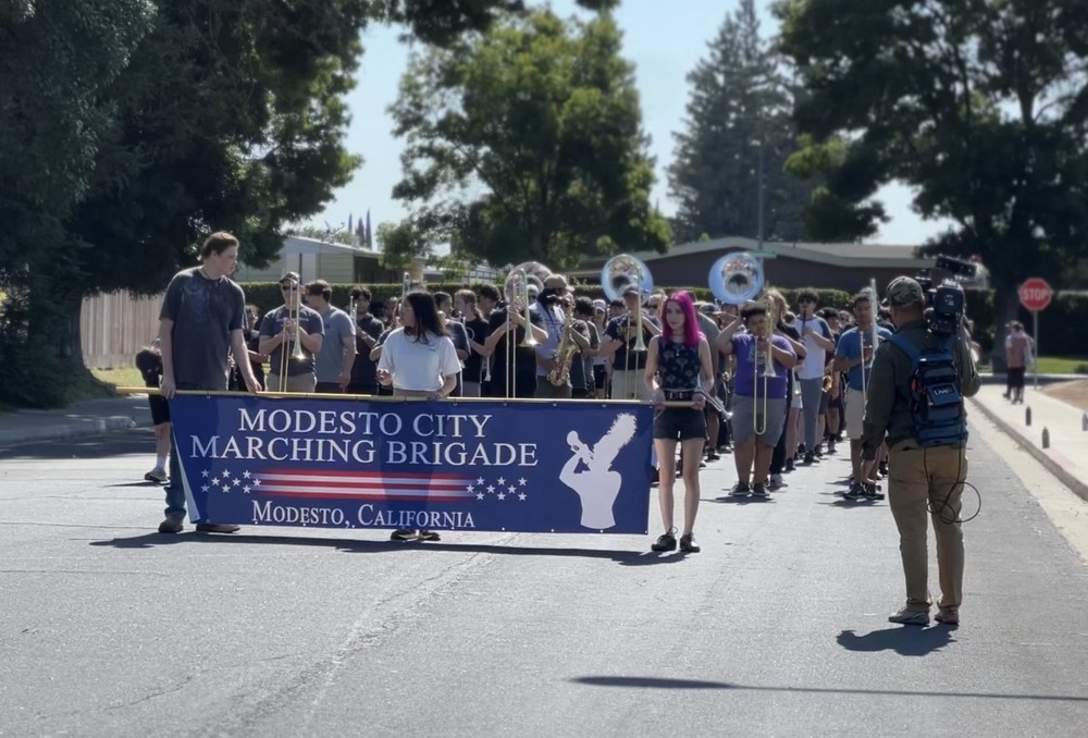Modesto City Marching Brigade holds large sign in front of Beyer High School