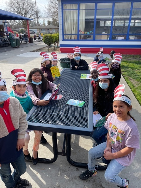several students around table with hats from dr seuss